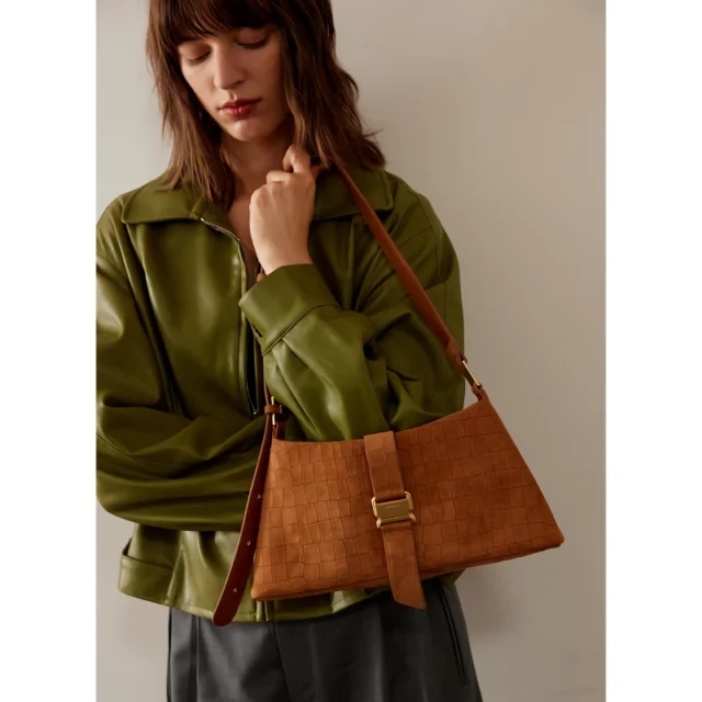 Lady holding a luxury leather handbag wearing green jacket