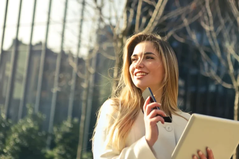 lady holding her phone and tablet in the sunshine looking to her right