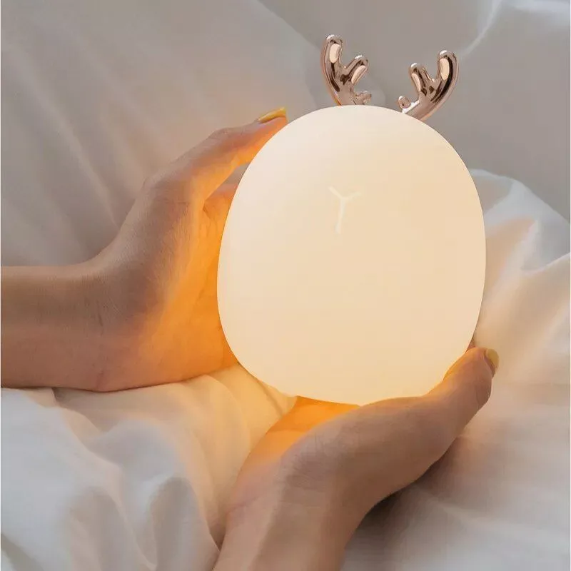 Lady holding a luminous bed lamp with reindeer horns